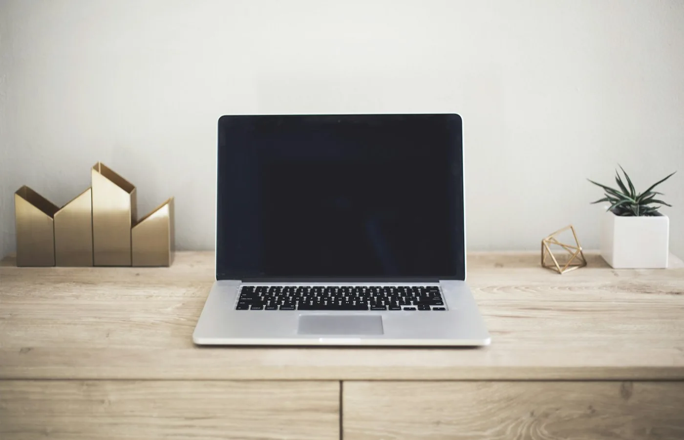 Geöffneter Laptop auf einem aufgeräumten Holztisch