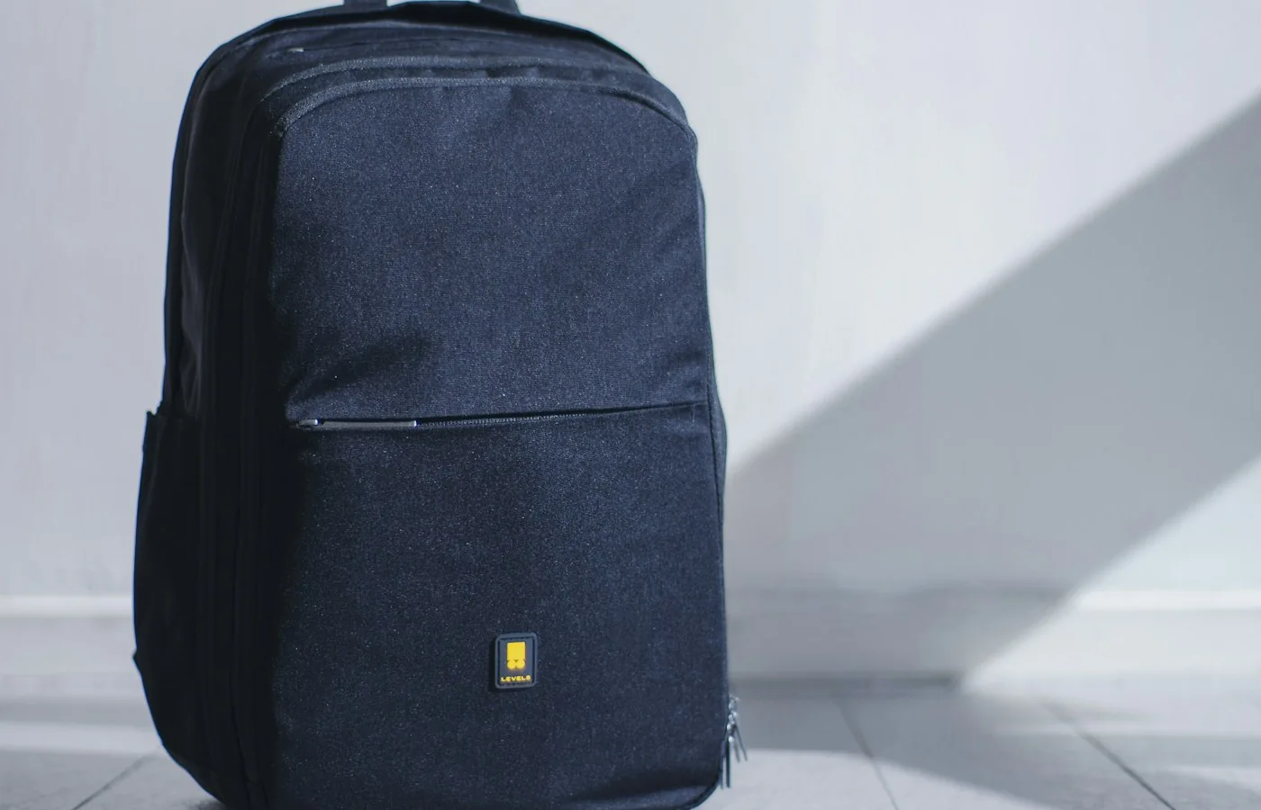 Dunkler Rucksack vor einer hellen Wand