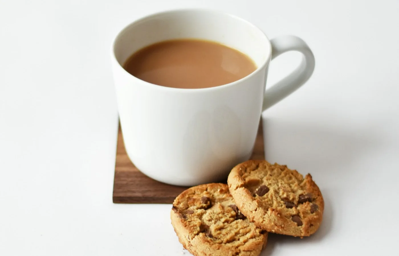 Helles Heißgetränk in einer weißen Tasse neben Keksen